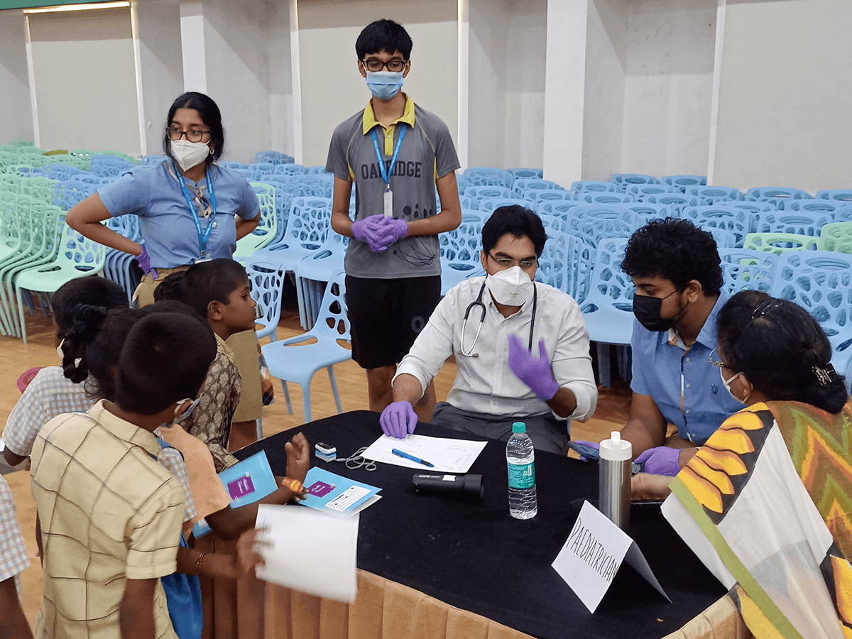 Paediatrician examining children with volunteers assisting at an outreach camp