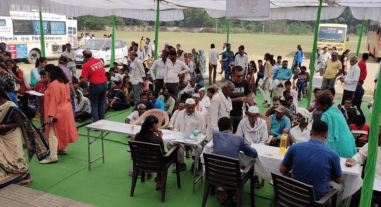 Large open-air health camp under a marquee with a mobile medical unit in attendance